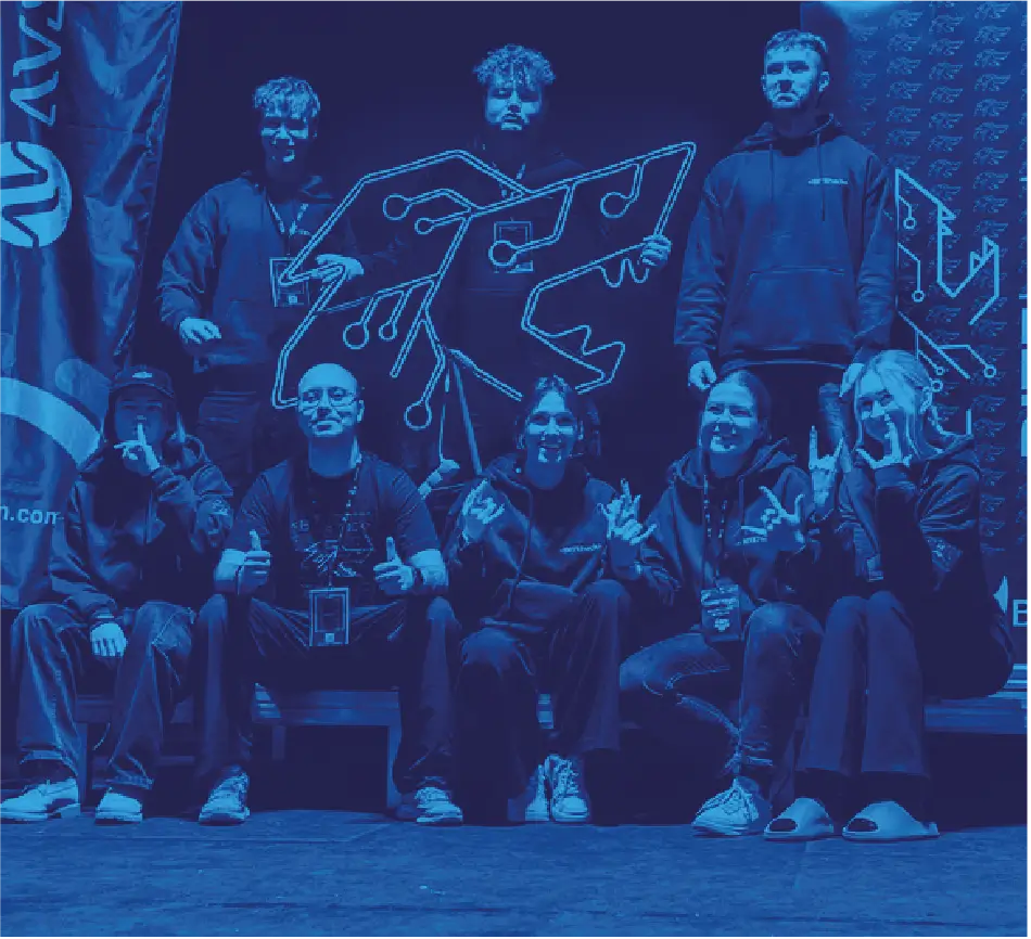 Pamiątkowe zdjęcie ośmioosobowej grupy organizatorów pozującej przed neonowym logo BITEhack.