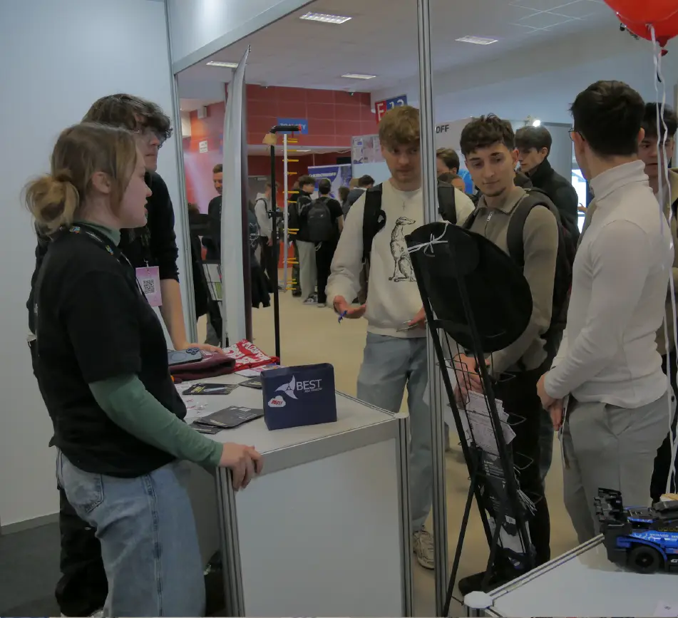 Studenci inżynierii rozmawiający z wystawcą przy stoisku firmy na Inżynierskich Targach Pracy
